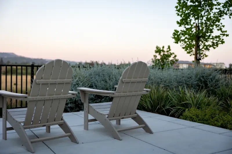 Two wooden chairs on a stone patio at dusk